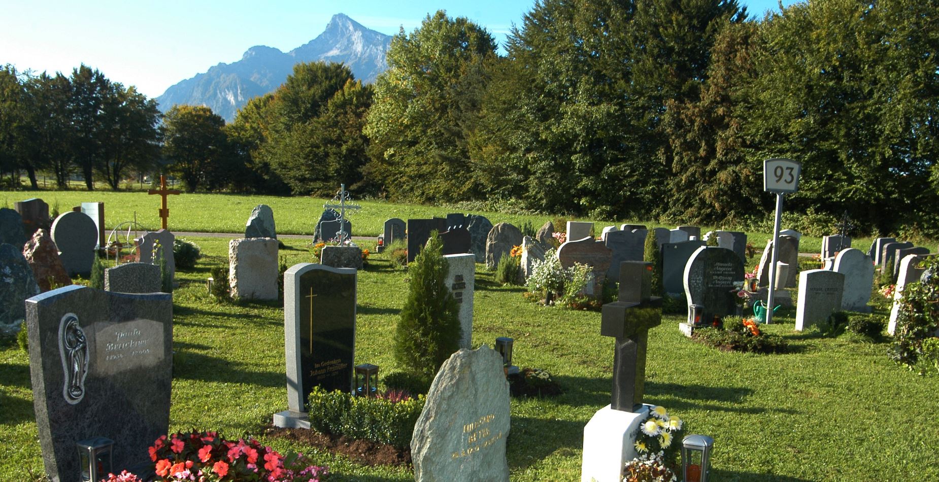 Vorsorgegräber vor schöner Landschaft mit Bäumen und Bergen.